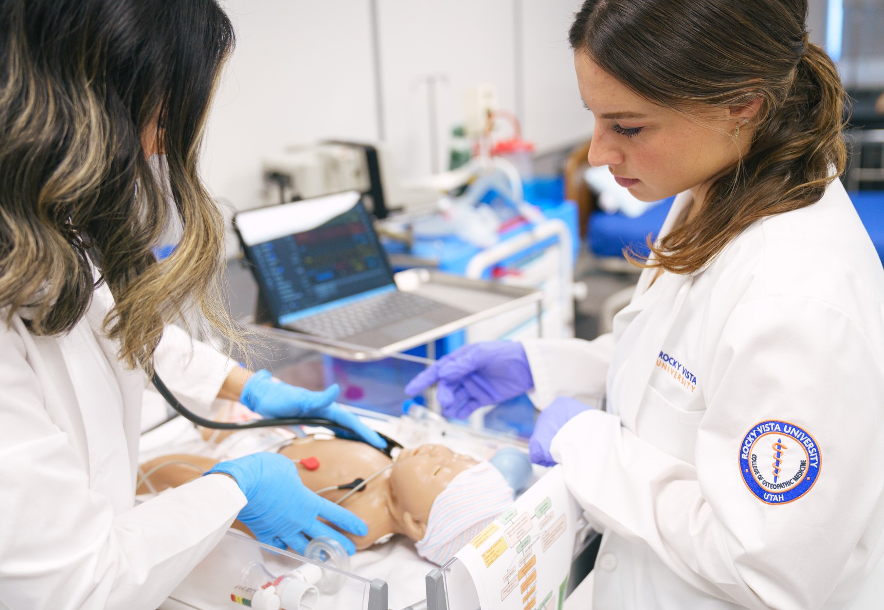 Two students at Rocky Vista University College of Osteopathic Medicine doing an exam on a pediatric medical manikin.