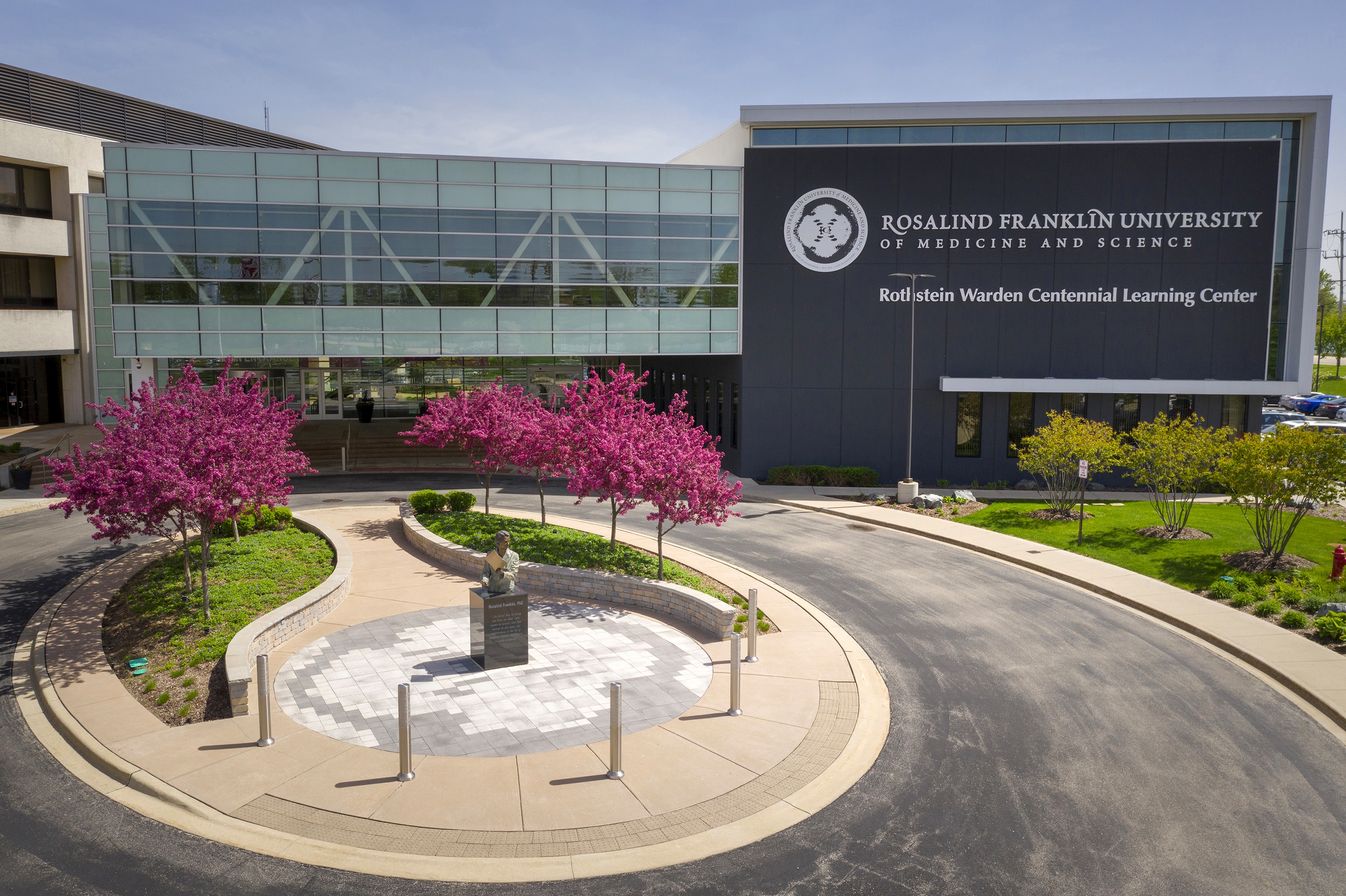 Outdoor view of a building that says Roselind Franklin University of Medicine and Science with some pink blossoming trees in front.