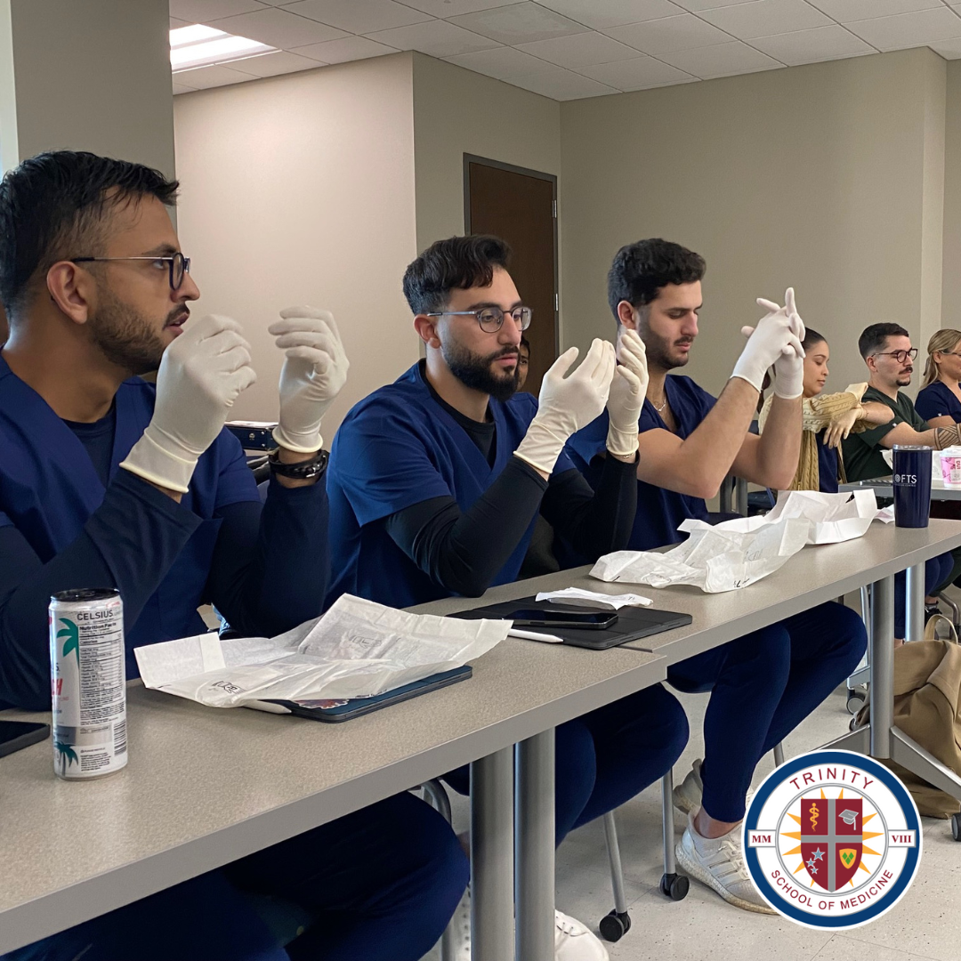 Students in the Trinity School of Medicine program practicing putting on sterile gloves.