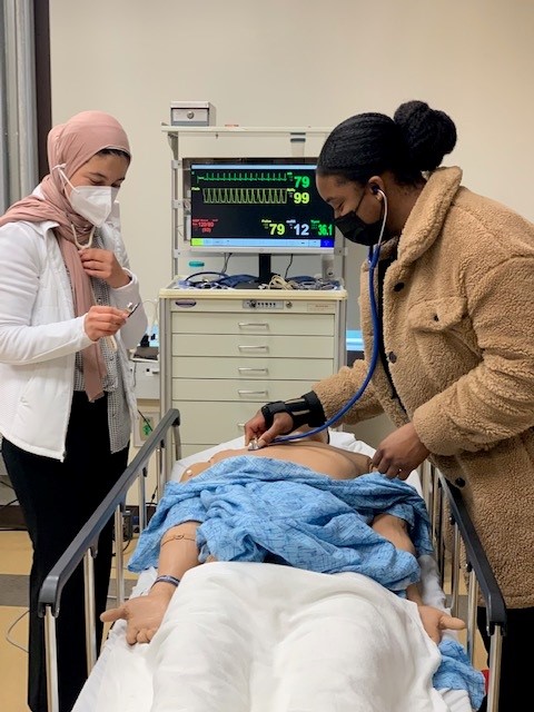 Two students in the UC Irvine School of Medicine program demonstrating an exam on a medical manikin.