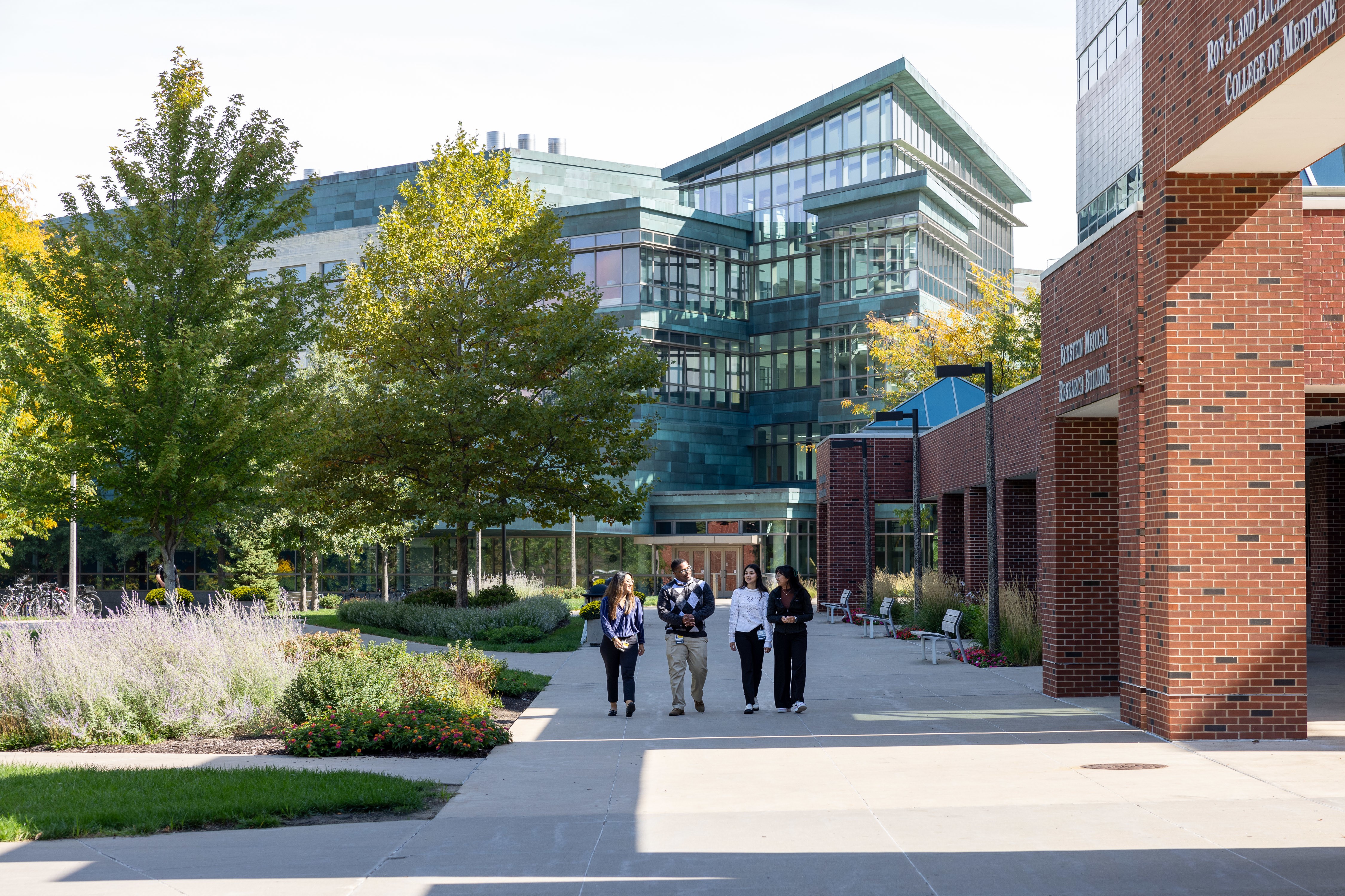 Four students walking in front of Iowa Carver College of Medicine building.