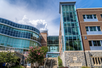 Modern glass and brick building with a blue sky and clouds overhead.