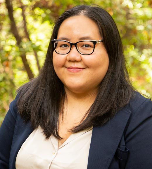 A photo of a woman with glasses and a blue blazer smiling at the camera.