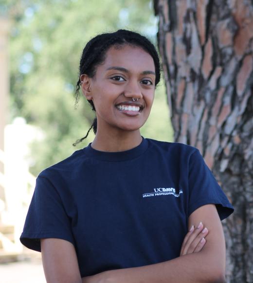 A photo of Rohan smiling at the camera and crossing her arms.